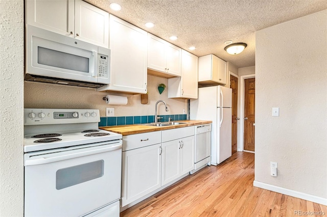 kitchen featuring butcher block counters, a sink, a textured ceiling, light wood-type flooring, and white appliances