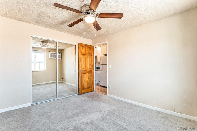 unfurnished bedroom with light carpet, baseboards, freestanding refrigerator, a textured ceiling, and a closet