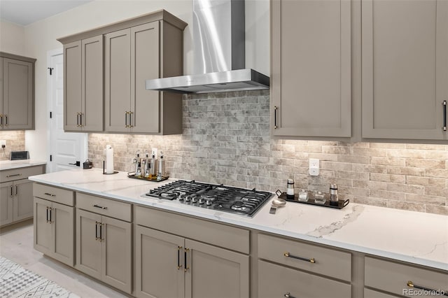 1881 Blossom Grove Dr, Windsor, CO 80550 - kitchen with wall chimney range hood, stainless steel gas stovetop, gray cabinetry, backsplash, and light stone counters