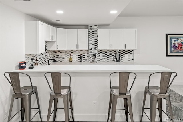 1881 Blossom Grove Dr, Windsor, CO 80550 - kitchen with light countertops, white cabinets, a kitchen bar, decorative backsplash, and recessed lighting