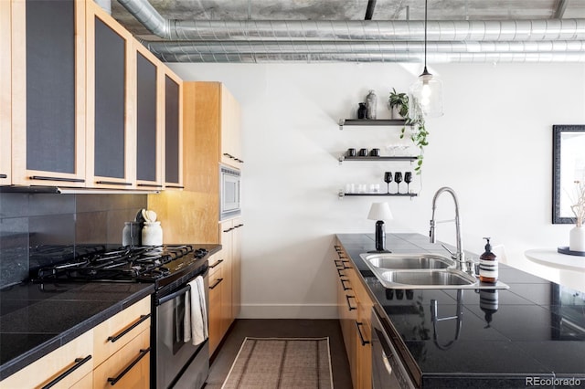 kitchen featuring stainless steel gas range, dark countertops, a sink, baseboards, and tasteful backsplash