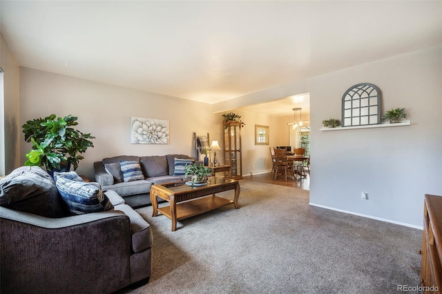 living area featuring baseboards, carpet flooring, and a chandelier