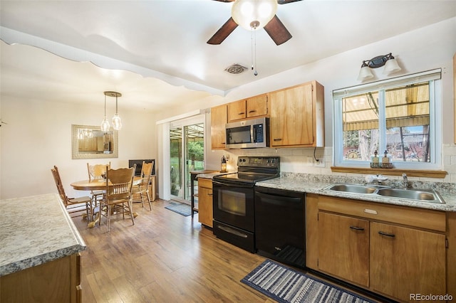 kitchen with visible vents, a sink, black appliances, and tasteful backsplash