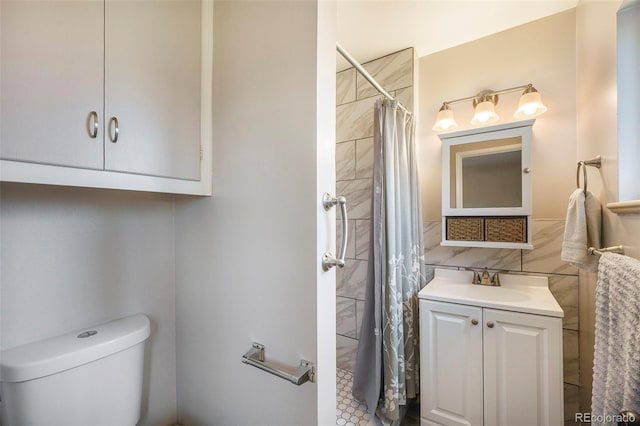 bathroom with vanity, toilet, tiled shower, and tile walls