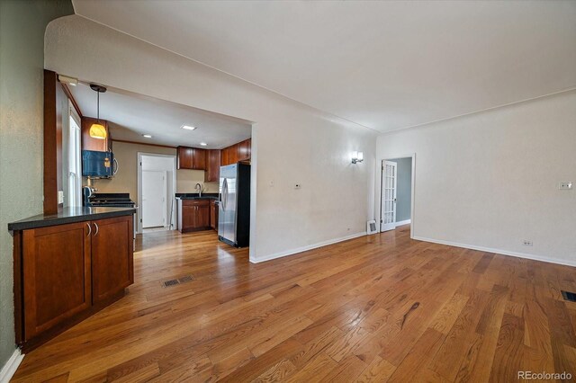 kitchen with dark countertops, open floor plan, wood finished floors, electric range, and stainless steel fridge