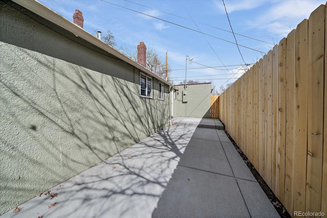 view of home's exterior featuring stucco siding, a chimney, fence, and a patio area