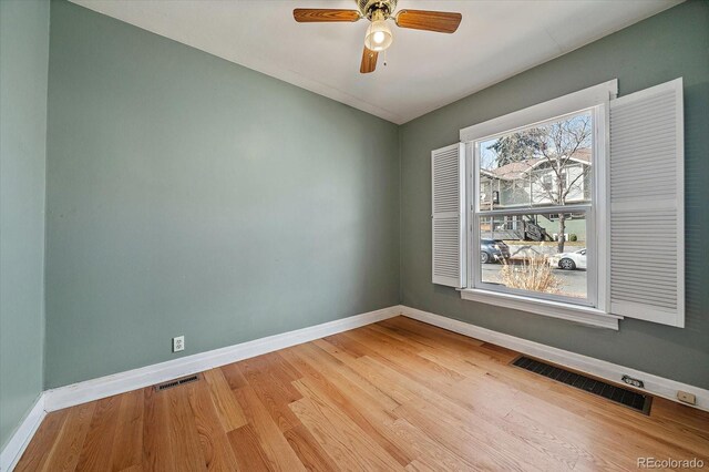empty room with baseboards, visible vents, wood finished floors, and ceiling fan