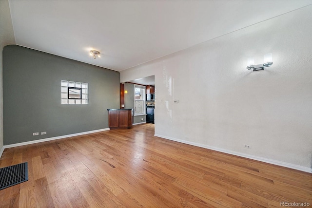 empty room featuring baseboards, visible vents, and light wood-type flooring