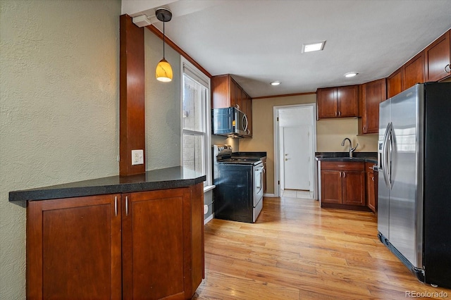 kitchen featuring light wood-type flooring, dark countertops, a textured wall, and stainless steel appliances