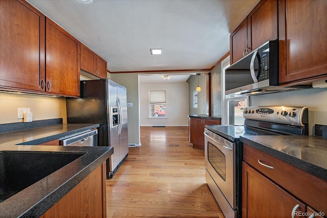 kitchen with crown molding, appliances with stainless steel finishes, brown cabinetry, baseboards, and light wood-style floors