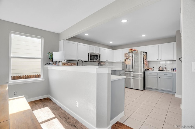 10521 Taylor Ave, Firestone, CO 80504 - kitchen with appliances with stainless steel finishes, backsplash, light countertops, white cabinets, and a peninsula