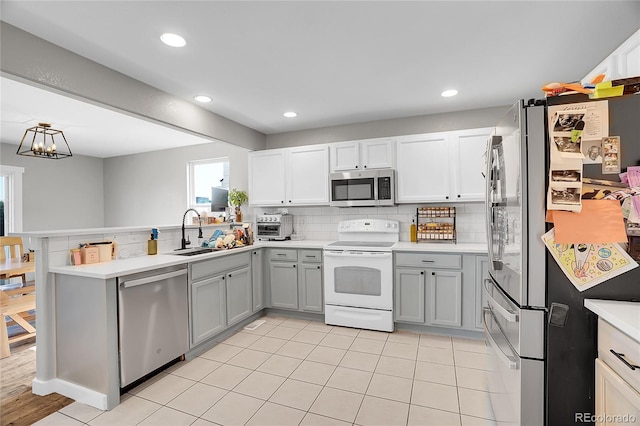 10521 Taylor Ave, Firestone, CO 80504 - kitchen with appliances with stainless steel finishes, a peninsula, light countertops, decorative backsplash, and gray cabinetry
