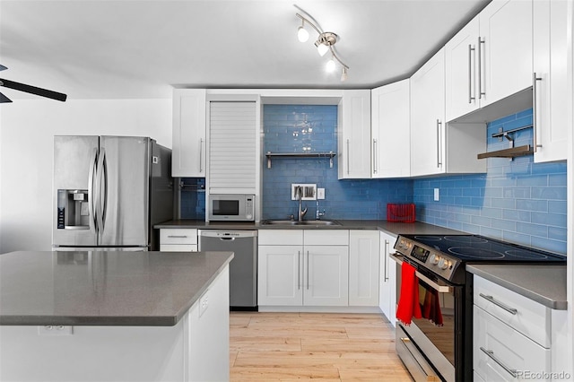 1121 Albion St Unit 210, Denver, CO 80220 - kitchen with stainless steel appliances, dark countertops, a sink, and light wood-style floors