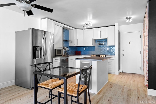 1121 Albion St Unit 210, Denver, CO 80220 - kitchen featuring stainless steel appliances, light wood finished floors, tasteful backsplash, dark countertops, and white cabinets