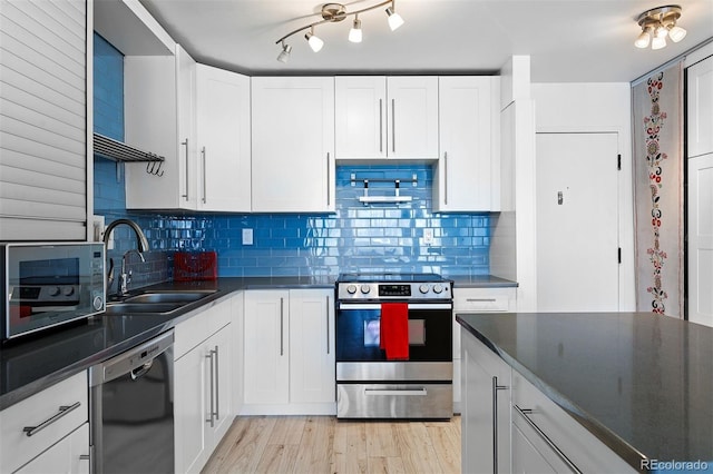 1121 Albion St Unit 210, Denver, CO 80220 - kitchen with appliances with stainless steel finishes, a sink, dark countertops, and white cabinets