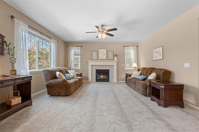 living room featuring ceiling fan, a tiled fireplace, and light carpet