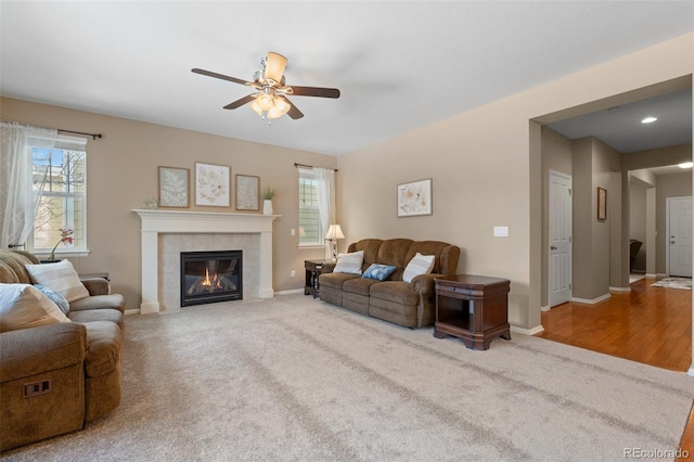 living room with ceiling fan, carpet floors, and a tile fireplace