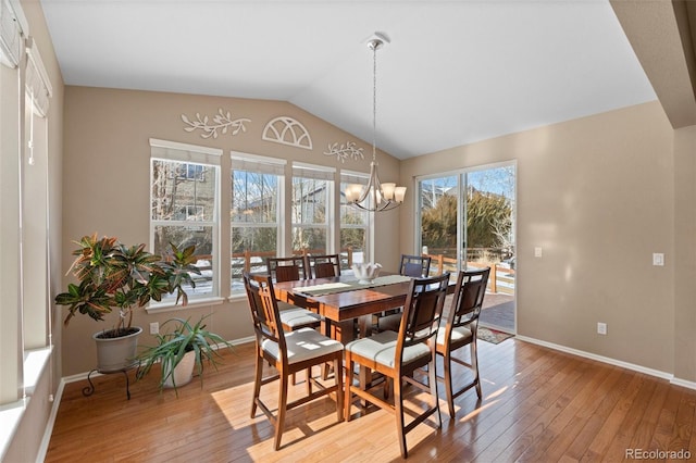 dining space featuring vaulted ceiling, a chandelier, and light hardwood / wood-style floors