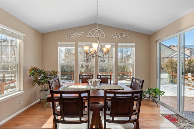 dining area with lofted ceiling, light hardwood / wood-style floors, and a chandelier