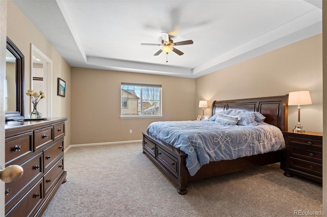 carpeted bedroom featuring a raised ceiling and ceiling fan