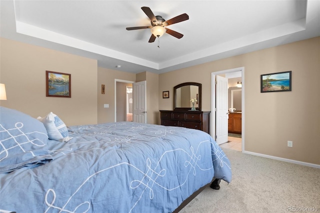 carpeted bedroom with connected bathroom, a tray ceiling, and ceiling fan