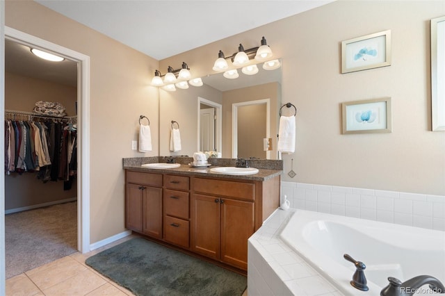 bathroom featuring tile patterned flooring, vanity, and tiled bath