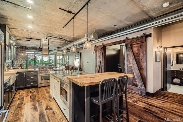 1401 Wewatta St Unit 308, Denver, CO 80202 - kitchen with stainless steel appliances, dark wood-style flooring, a barn door, butcher block counters, and a breakfast bar