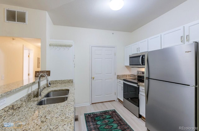 2428 W 82nd Pl Unit 3G, Westminster, CO 80031 - kitchen with appliances with stainless steel finishes, white cabinets, light wood-type flooring, and light stone countertops