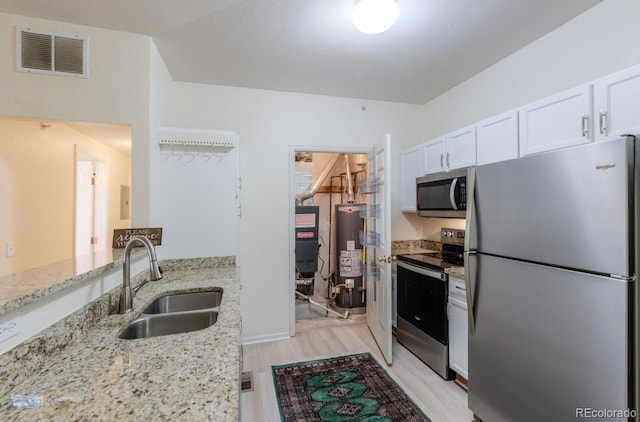 2428 W 82nd Pl Unit 3G, Westminster, CO 80031 - kitchen featuring stainless steel appliances, gas water heater, white cabinetry, light stone countertops, and light wood finished floors