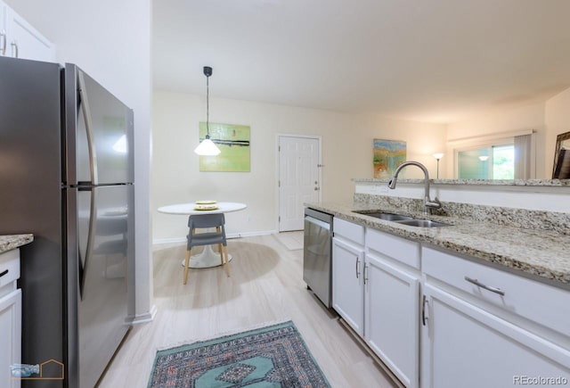 2428 W 82nd Pl Unit 3G, Westminster, CO 80031 - kitchen with appliances with stainless steel finishes, white cabinetry, light wood finished floors, light stone countertops, and decorative light fixtures