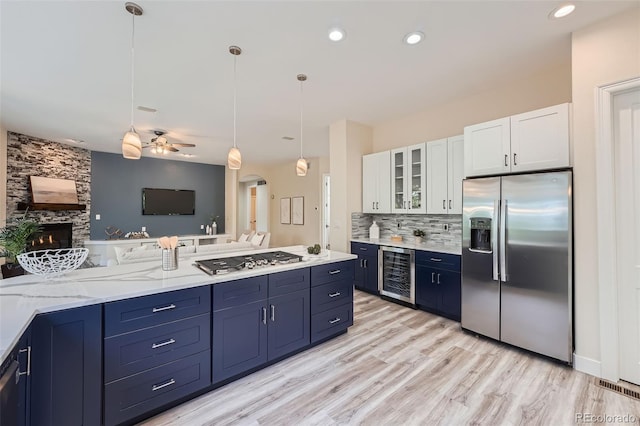 22019 E Arbor Dr, Aurora, CO 80016 - kitchen with appliances with stainless steel finishes, beverage cooler, blue cabinets, white cabinetry, and glass insert cabinets