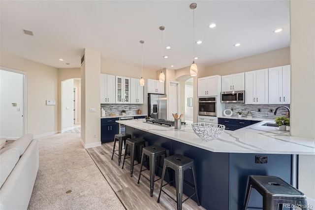 22019 E Arbor Dr, Aurora, CO 80016 - kitchen with arched walkways, stainless steel appliances, a breakfast bar, backsplash, and recessed lighting