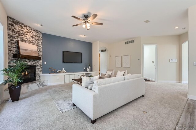 22019 E Arbor Dr, Aurora, CO 80016 - living room featuring a ceiling fan, a stone fireplace, arched walkways, carpet flooring, and recessed lighting