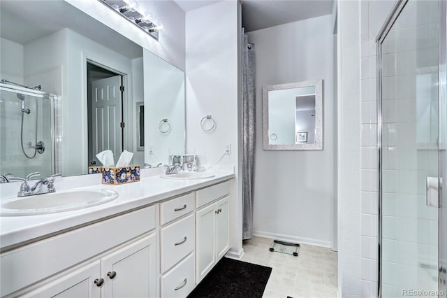 full bathroom featuring double vanity, a shower stall, baseboards, and a sink