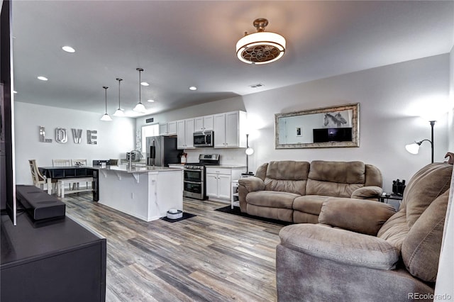 living area featuring recessed lighting, visible vents, and wood finished floors