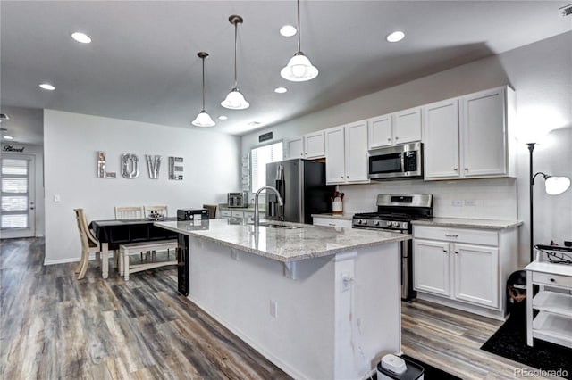 kitchen featuring light stone counters, dark wood finished floors, backsplash, appliances with stainless steel finishes, and white cabinets