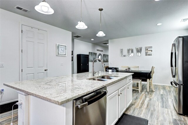 kitchen featuring visible vents, appliances with stainless steel finishes, white cabinetry, a sink, and light wood-type flooring