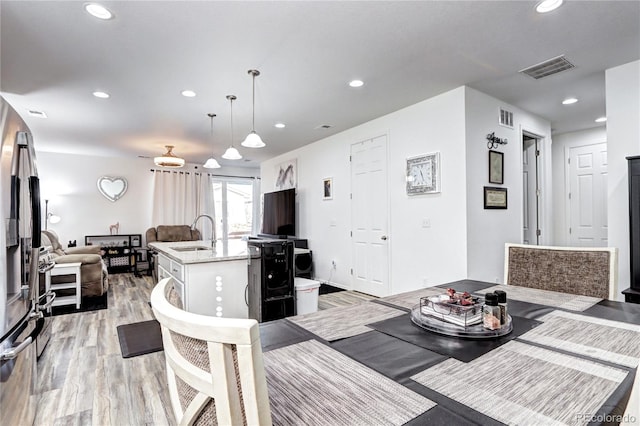 dining area with light wood finished floors, visible vents, and recessed lighting