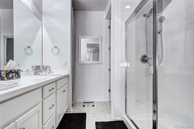 bathroom featuring baseboards, double vanity, a sink, and a shower stall