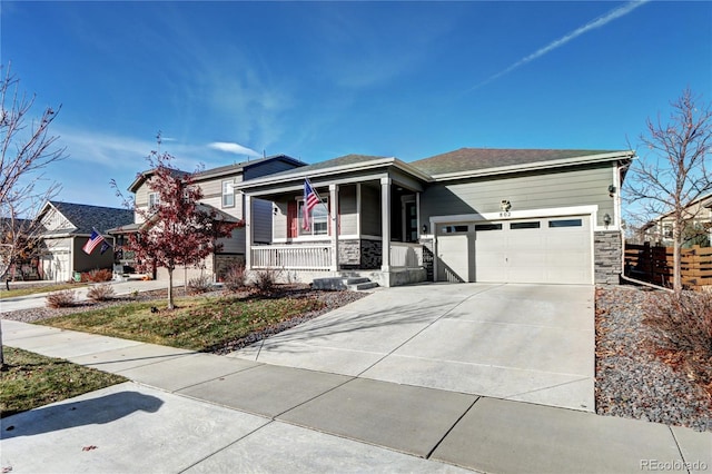 view of front of house featuring stone siding, covered porch, a garage, and concrete driveway