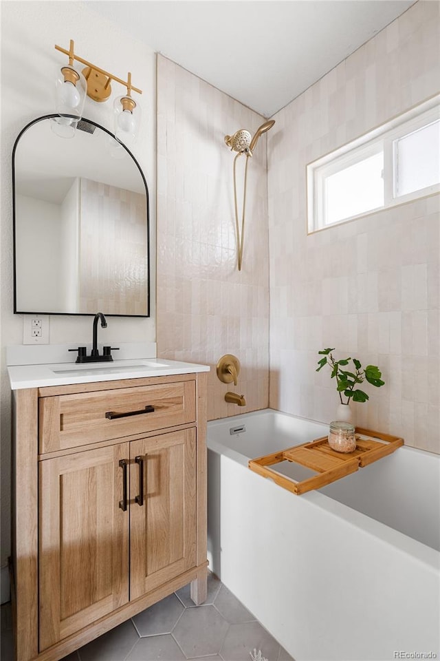 bathroom with tile patterned flooring, vanity, tile walls, and tub / shower combination