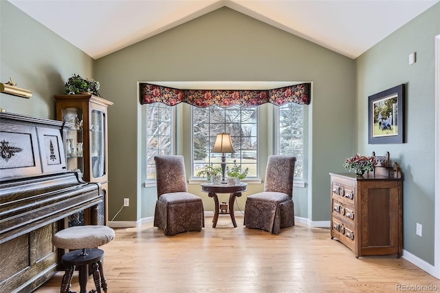 sitting room featuring light wood-type flooring, baseboards, and lofted ceiling