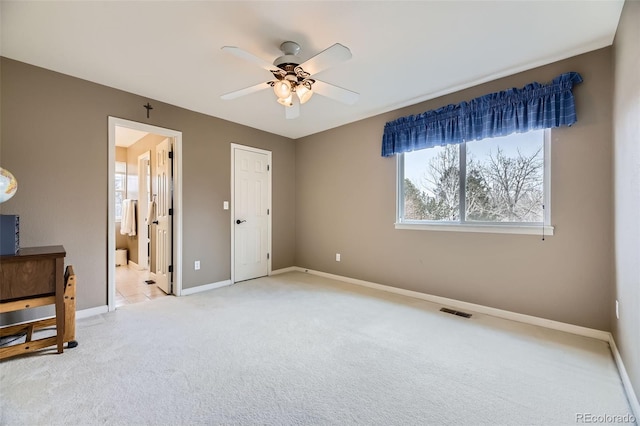 bedroom with visible vents, light colored carpet, connected bathroom, and baseboards