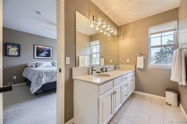 ensuite bathroom featuring baseboards, double vanity, a sink, and ensuite bathroom