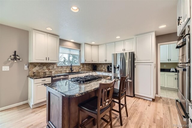 2522 W Dry Creek Ct, Littleton, CO 80120 - kitchen with stainless steel appliances, a sink, white cabinetry, a kitchen bar, and recessed lighting