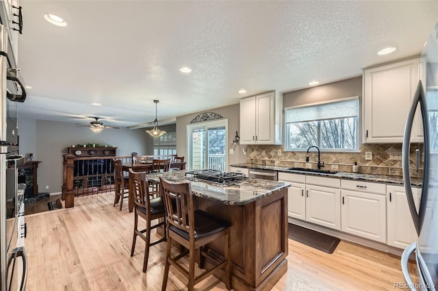 2522 W Dry Creek Ct, Littleton, CO 80120 - kitchen featuring a sink, light wood-type flooring, a breakfast bar, white cabinets, and recessed lighting
