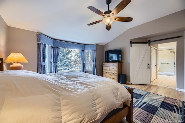 2522 W Dry Creek Ct, Littleton, CO 80120 - bedroom featuring lofted ceiling, a barn door, wood finished floors, baseboards, and connected bathroom