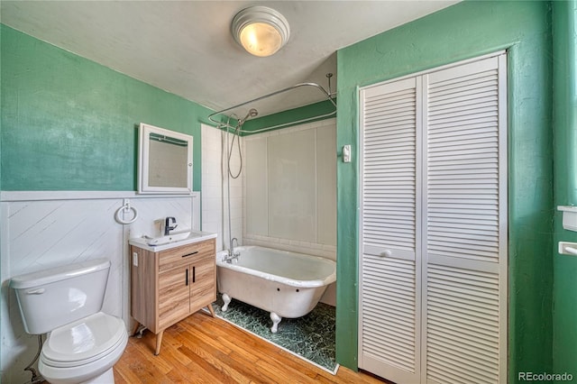full bathroom with toilet, wood finished floors, a closet, a wainscoted wall, and vanity