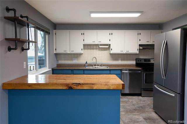 kitchen featuring stainless steel appliances, white cabinetry, sink, and butcher block countertops