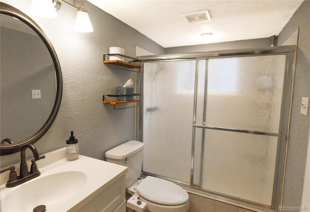 bathroom with vanity, a shower with door, and toilet